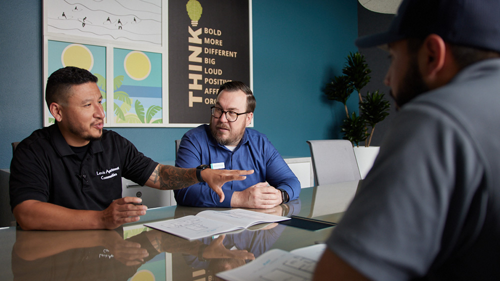 Three men engaged in a lively conversation while sitting at a table.