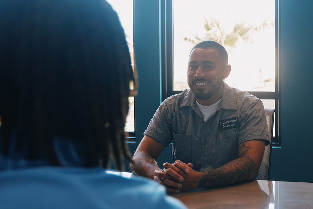 A man engaged in conversation with another man at a table.